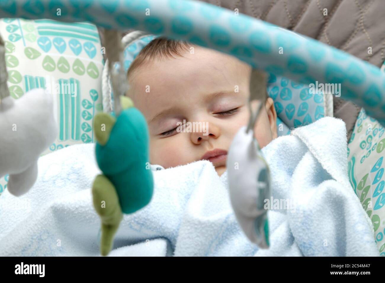 Baby sleeping in a rocking chair covered with a blanket. Stock Photo