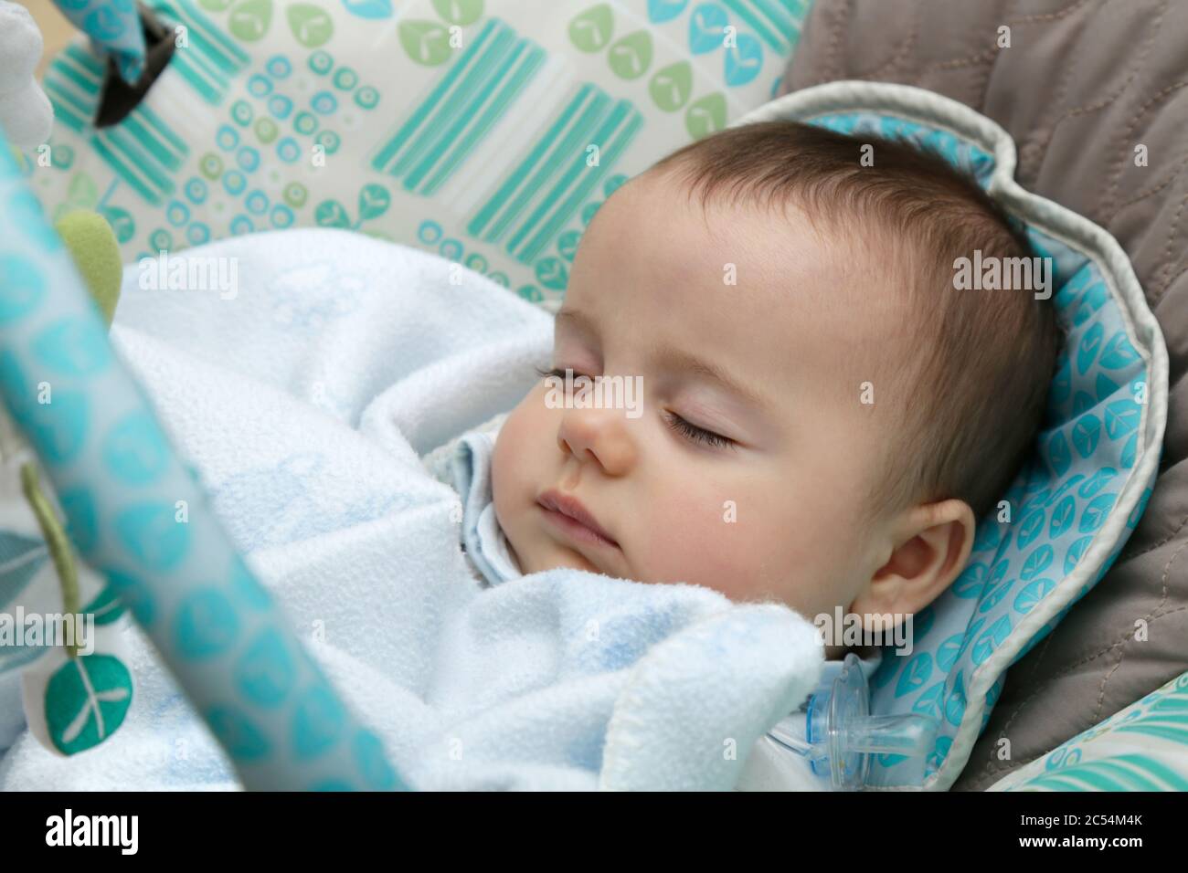 Baby sleeping in a rocking chair covered with a blanket. Stock Photo
