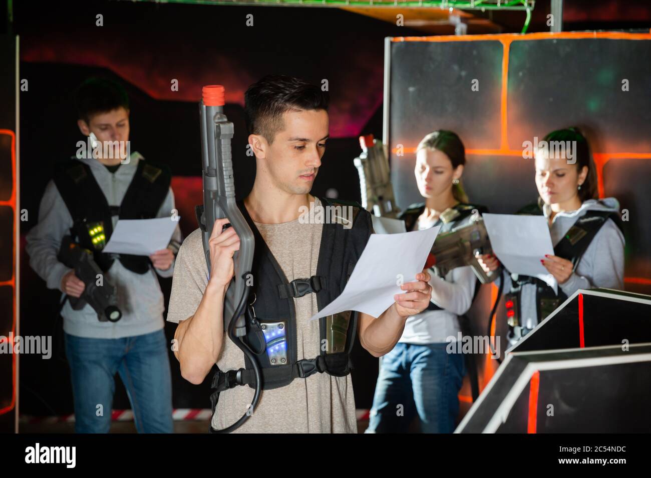 Focused young man in full laser tag equipment carefully reading rules of  game before playing on lasertag arena Stock Photo - Alamy