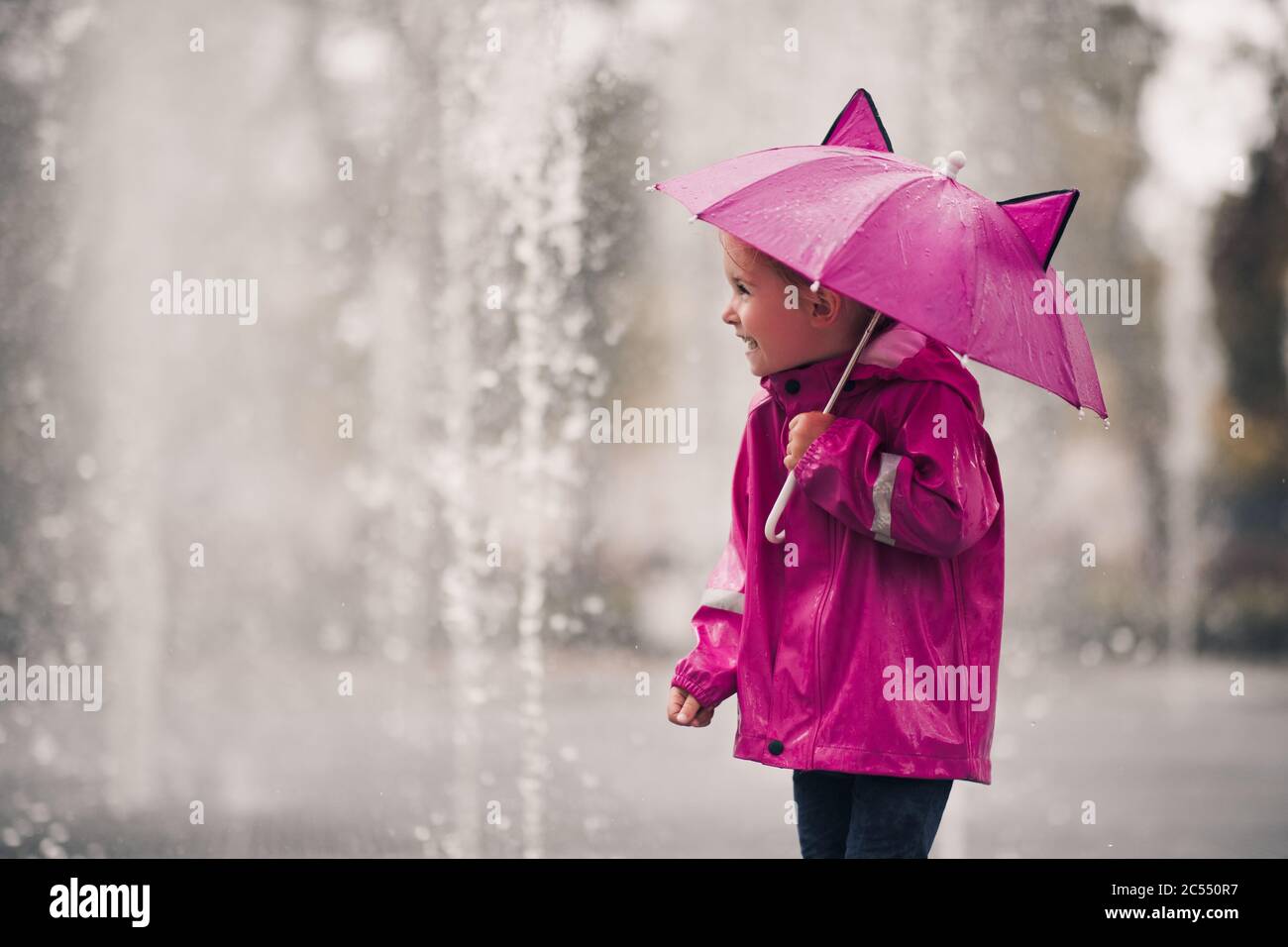 Happy child girl 4-5 year old holding pink umbrella wearing raincoat over  rain at background outdoors. Autumn season. Childhood Stock Photo - Alamy