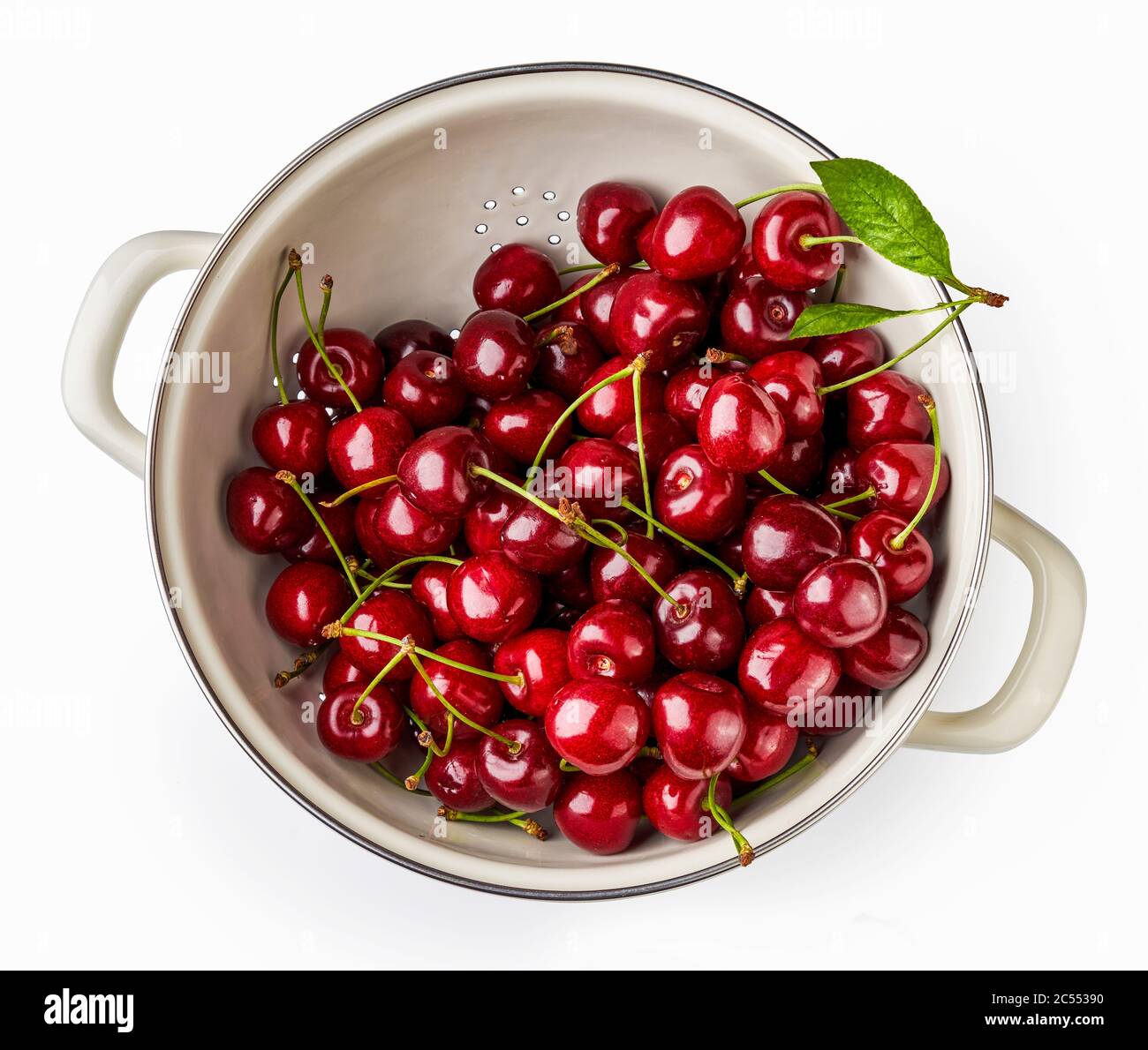 White strainer with fresh cherries isolated on a white background. Top view of colander with berries. Stock Photo