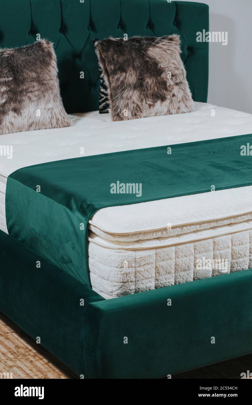 Vertical shot of a queensize bed with green velvet headboard and