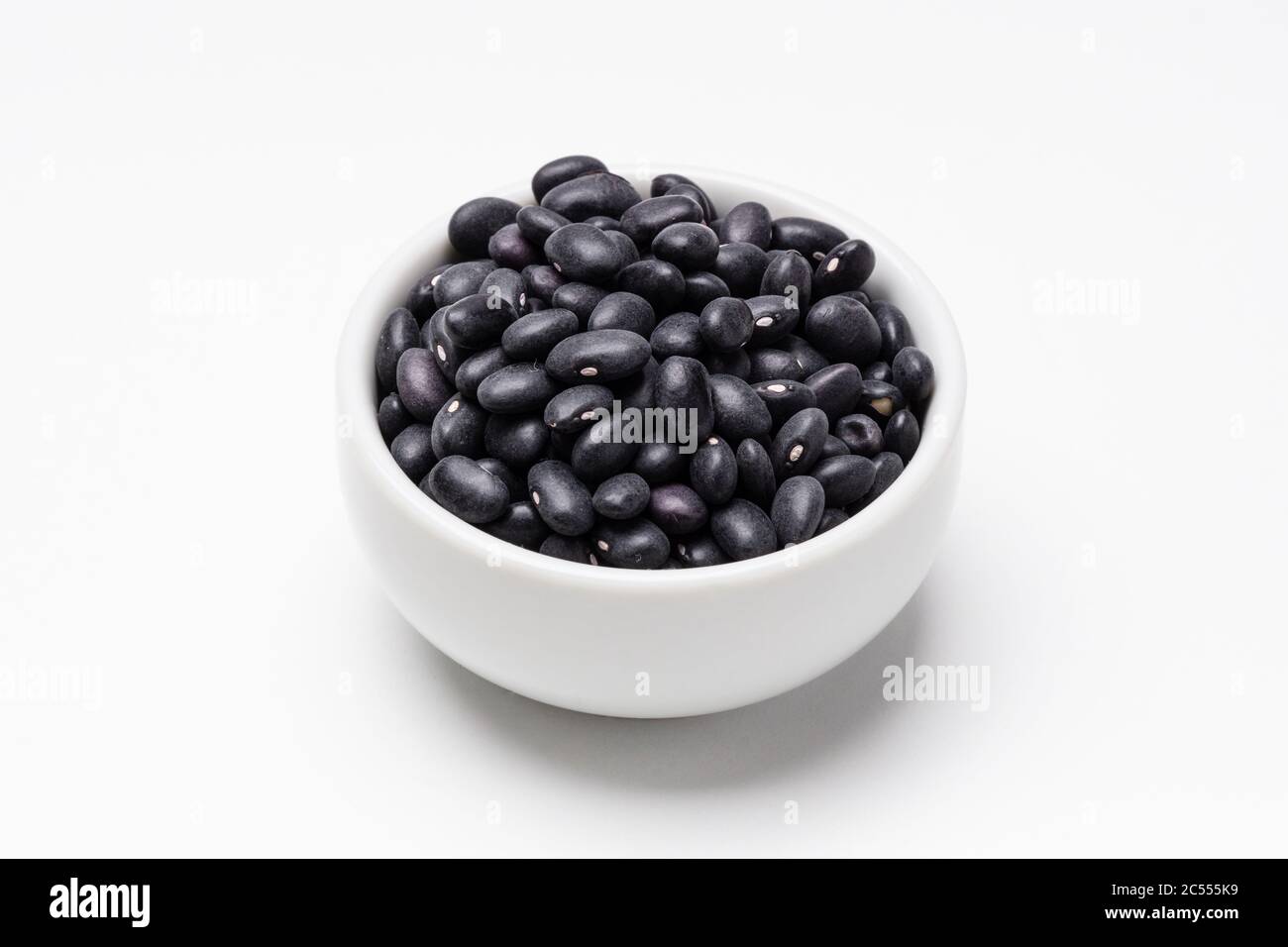 Black turtle beans bowl on white background. These uncooked black beans