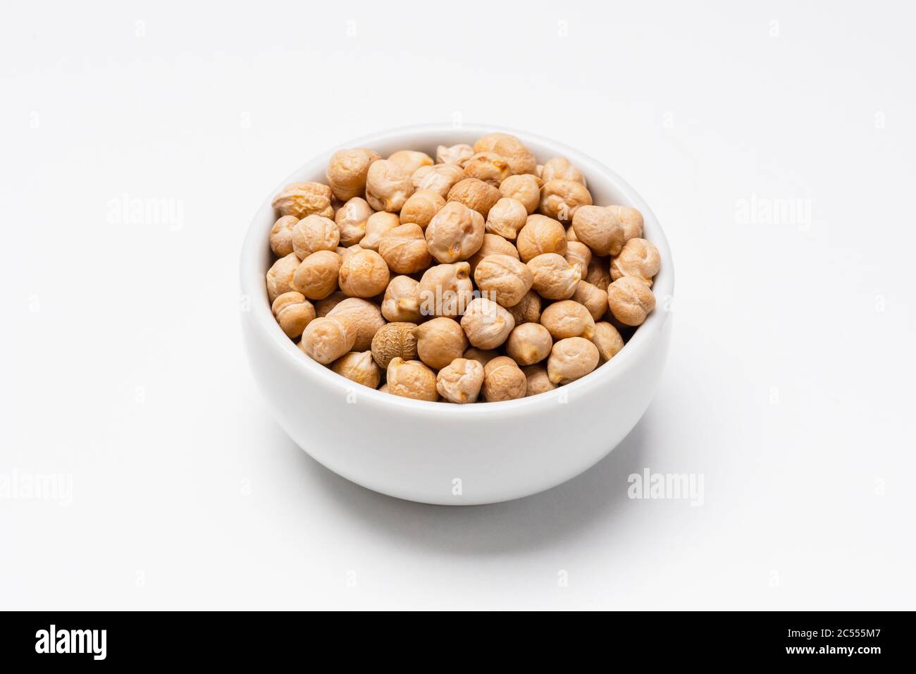 Chickpeas bowl on white background. These uncooked chickpeas are common staple food ingredients. Also called pulses (dry edible seeds of plants), they Stock Photo