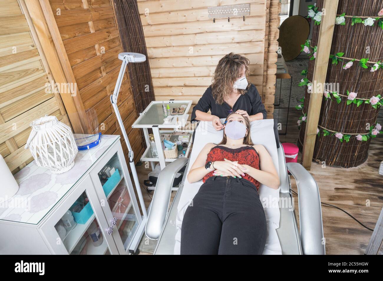 beautician working with mask and protective screen for the virus COVID Stock Photo