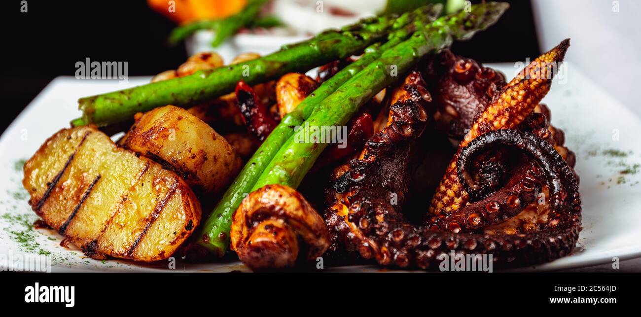 Closeup shot of a delicious octopus dish with roasted  mushrooms, potatoes, and asparagus Stock Photo