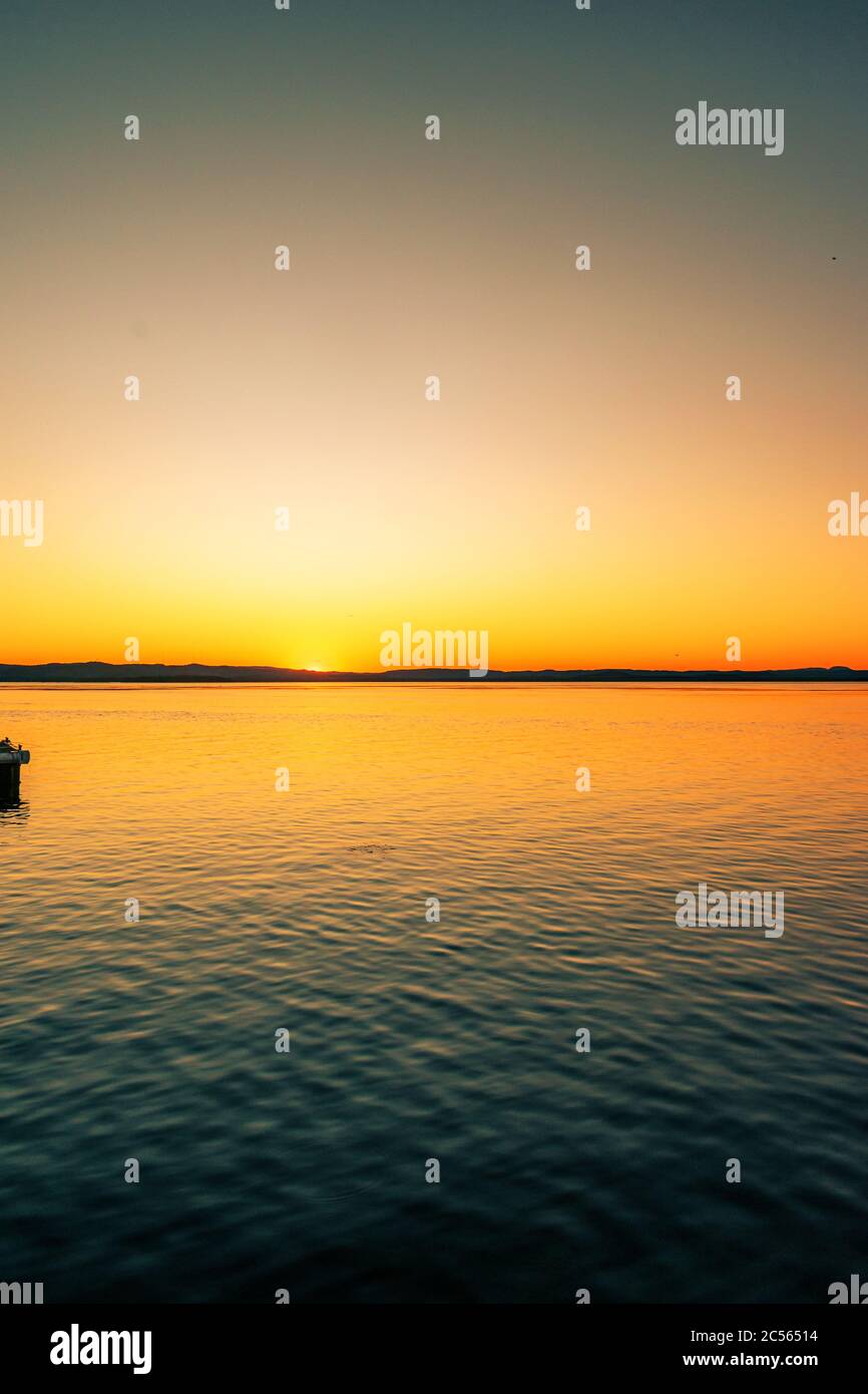 Breathtaking scenery of the sunset sky reflecting in the peaceful sea ...