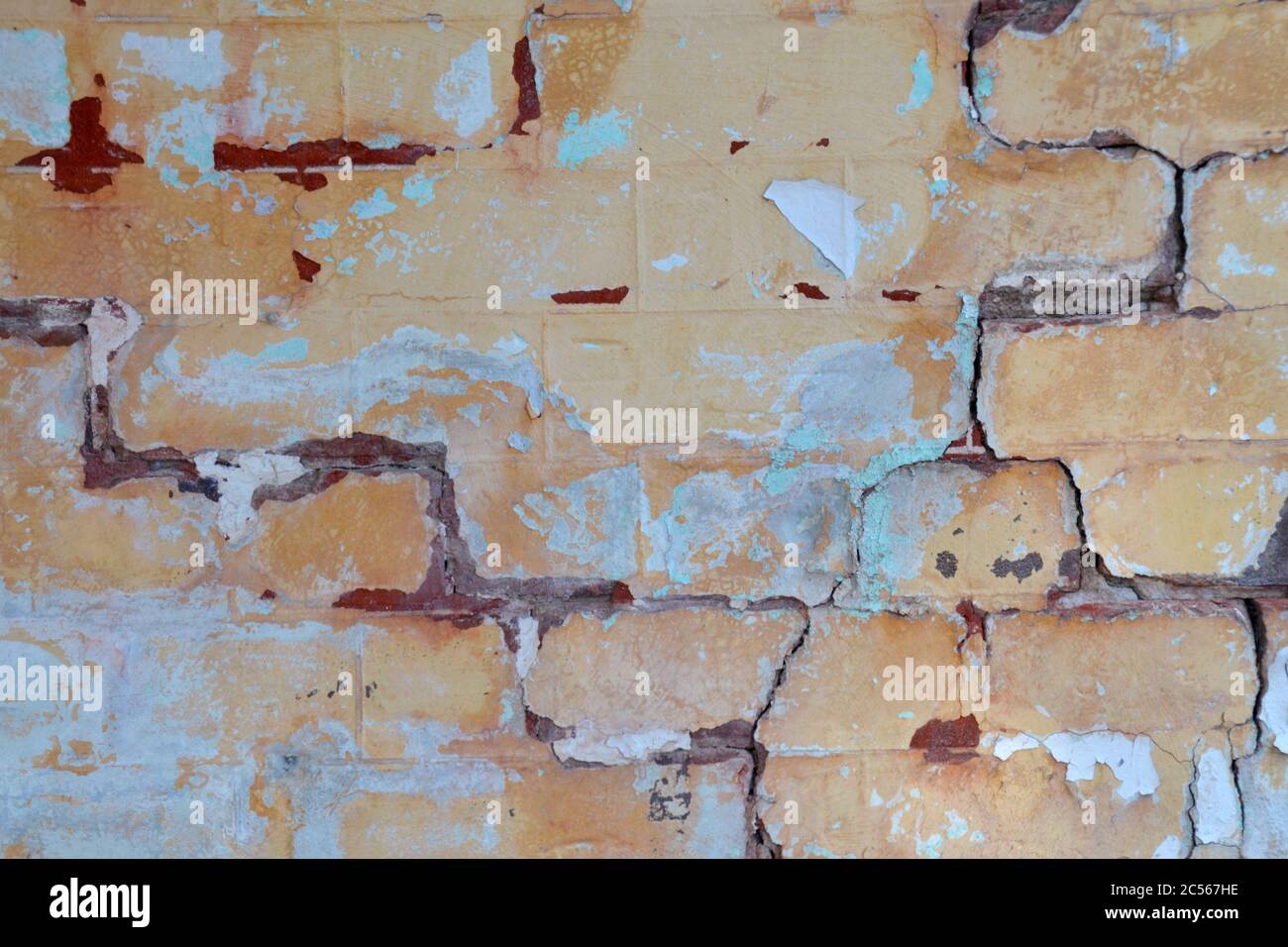 Old vintage powder blue peeling paint on a brick wall with cracks in disrepair Stock Photo