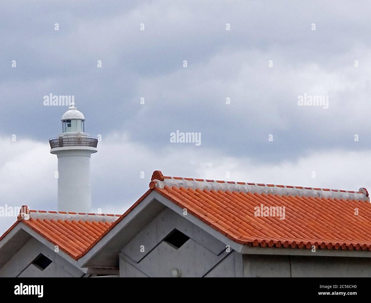 Cape Zanpa lighthouse and its adjascent red tiled roof buildings on a cloudy day in Okinawa, Japan Stock Photo