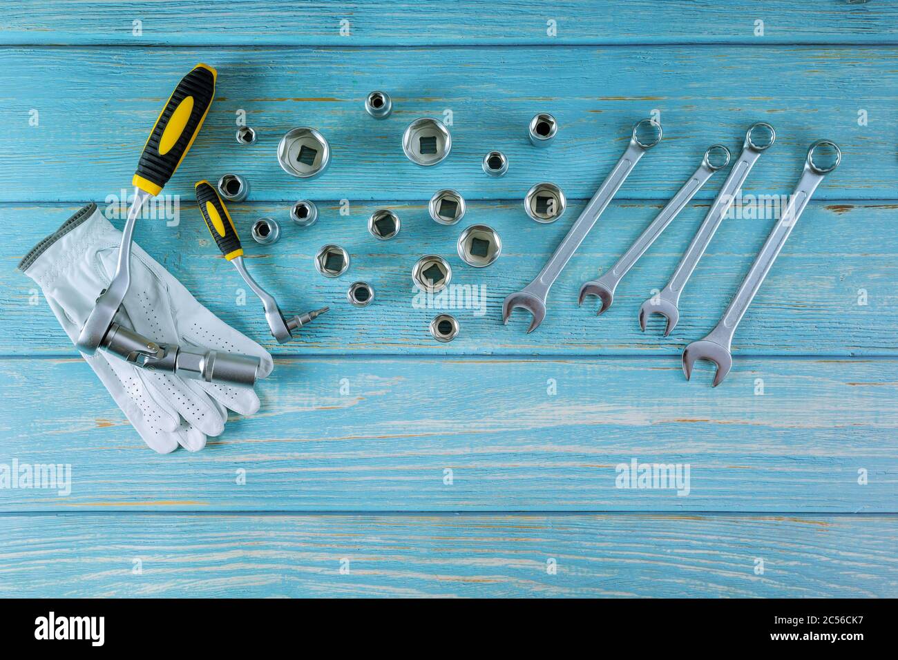 A set of hexagons of different sizes with working gloves in automotive set of wrenches for car repair auto mechanic a wooden blue background Stock Photo