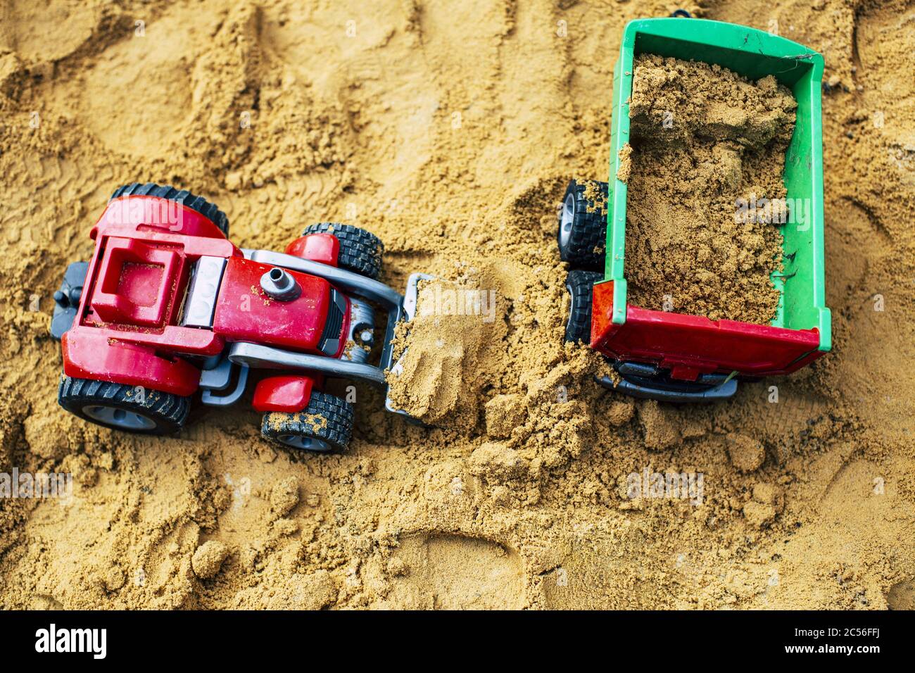 Top view of loader and dump truck toys on a mound of soil. Concept of childhood Stock Photo