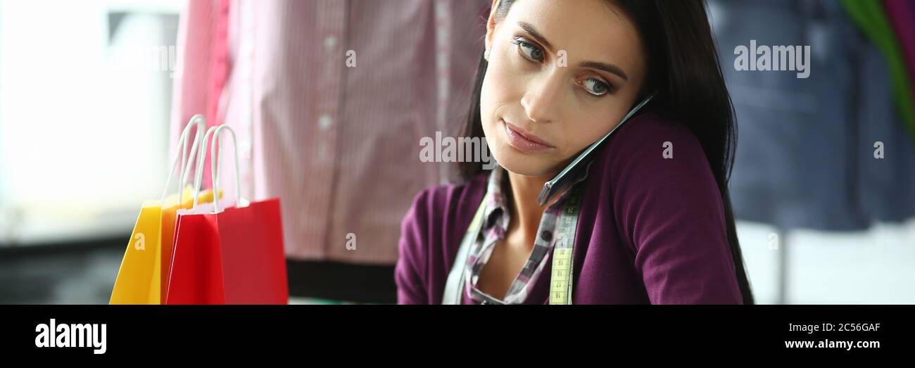 Tailor talking on phone with client in workshop. Stock Photo