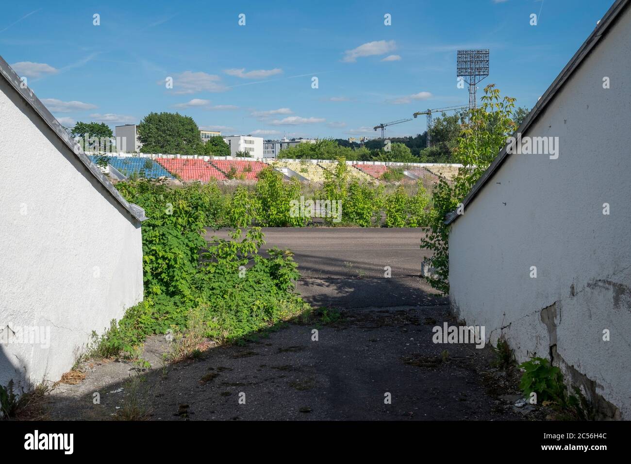 A look through a gate to the overgrown field and colorful stands at Žalgiris Stadium, now torn down. In Vilnius, Lithuania. Stock Photo