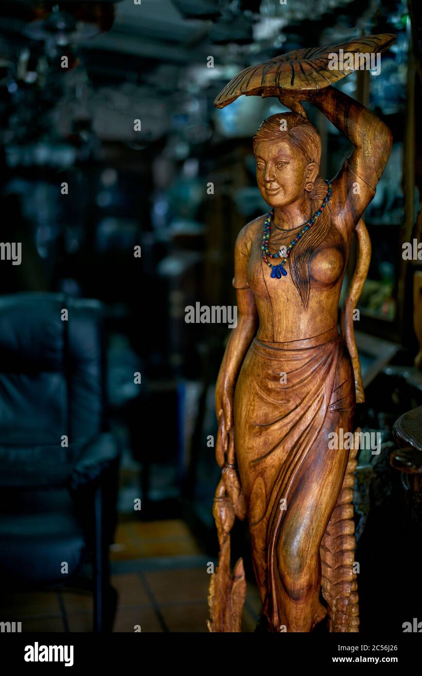 Antique Thailand. Wooden figure of a woman sheltering from the rain beneath large liily pad . Thailand, Asian, antiques Stock Photo