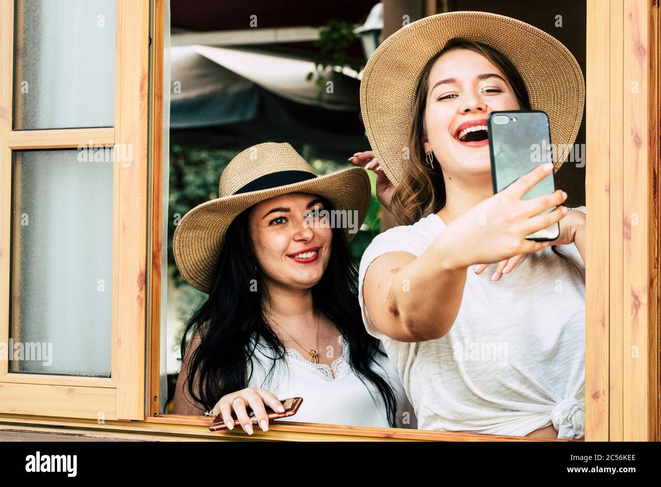 Pretty young curvy girls have lot of fun together in friendship taking selfie picture with modern big phone cellular to share on social media - infleu Stock Photo