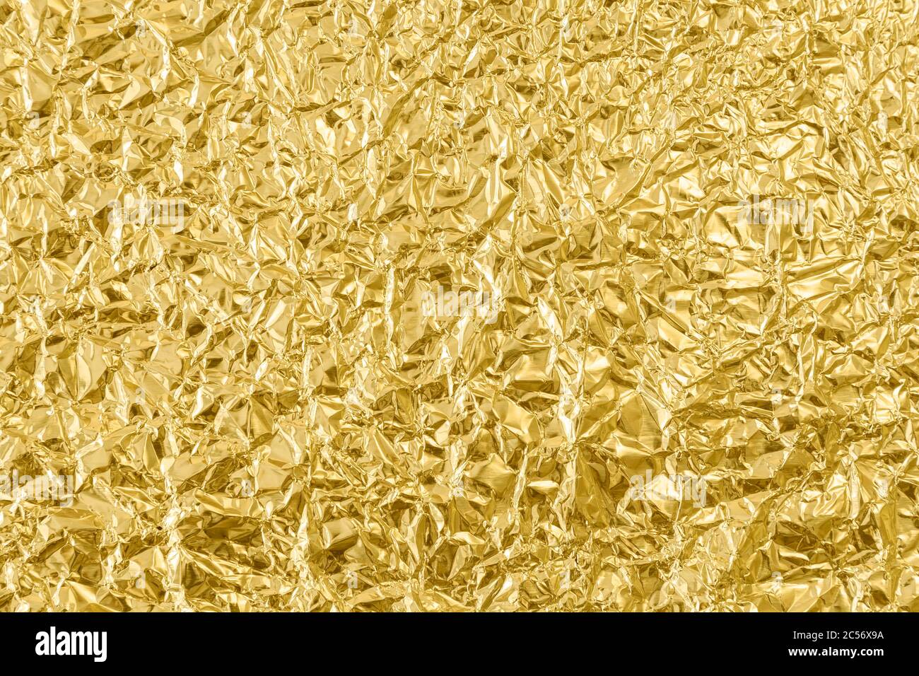 Close-up of a crumpled golden tin foil surface, top view. Abstract full frame textured silvery background. Stock Photo