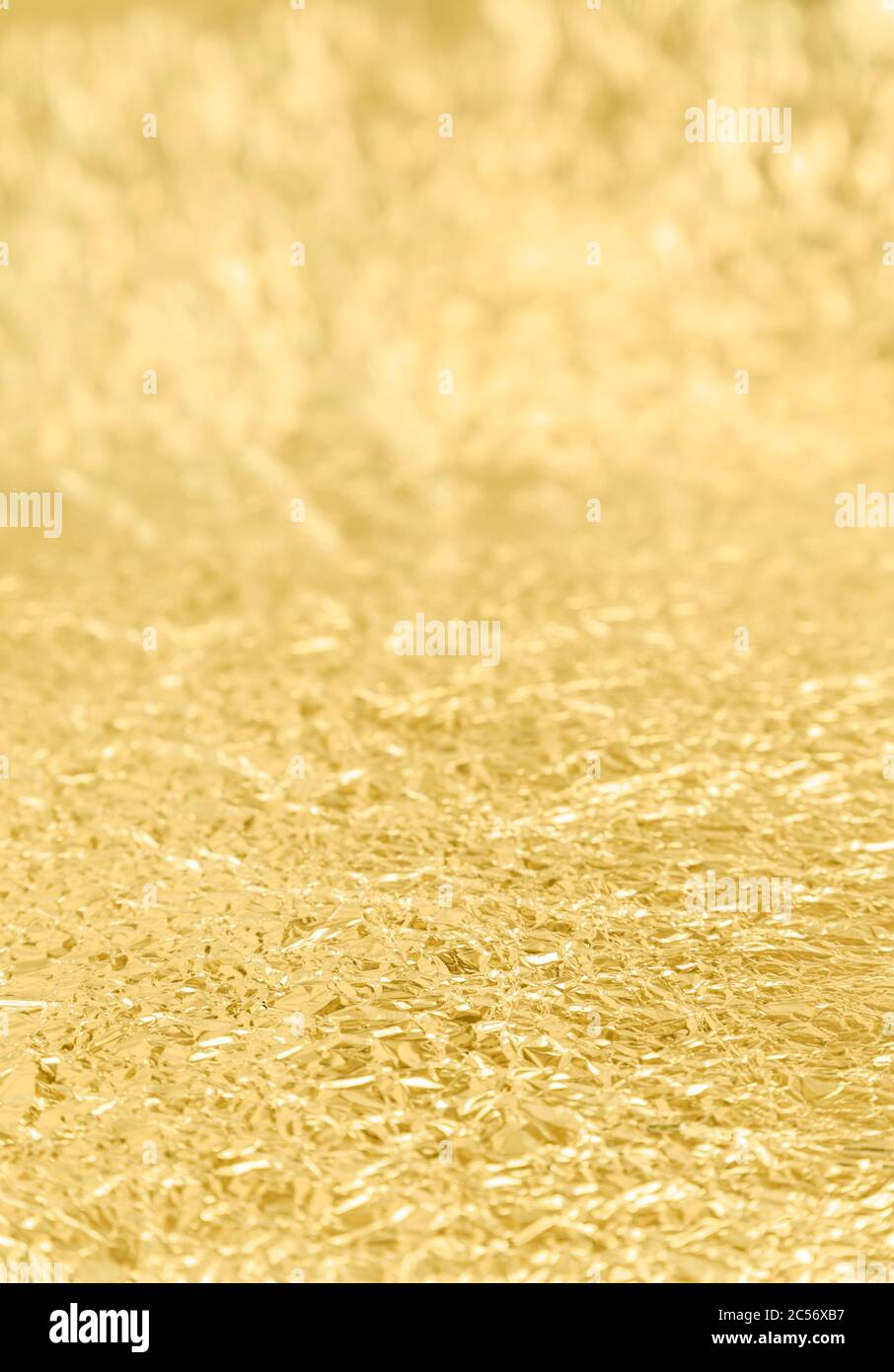 Close-up of crumpled golden tin foil surface. Focused on the front, selective focus. Abstract full frame textured background. Stock Photo