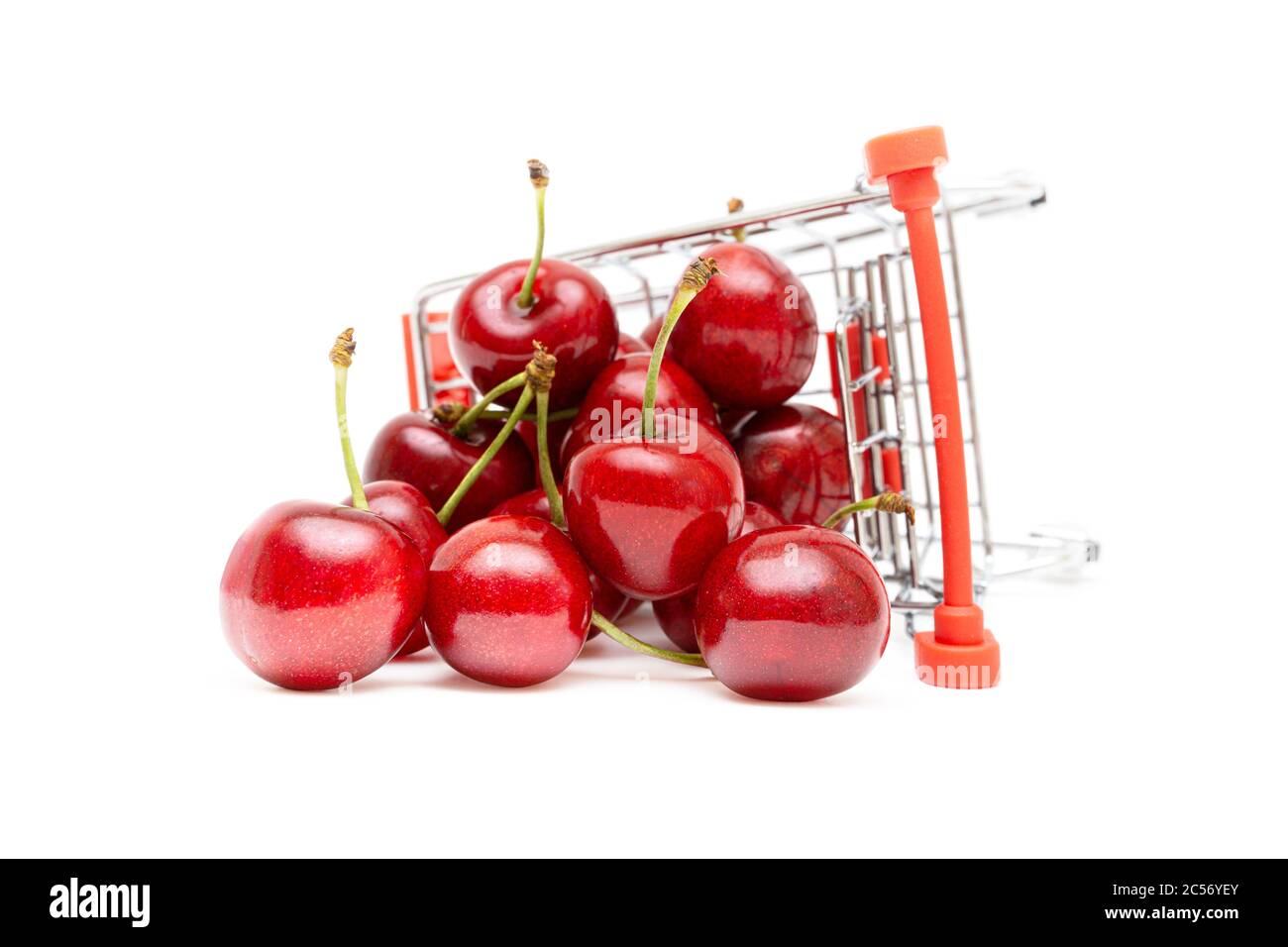 Closeup of sweet cherries in a miniature toy shopping trolley isolated on white background. Fresh fruit delivery concept. Stock Photo