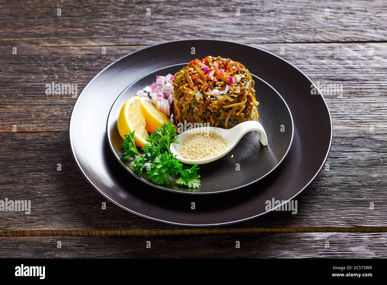 Healthy Japanese Food Salad Of Marinated Wakame Seaweed With Oil Red Onion And Lemon Wedges Served On A Black Plate With Curly Parsley Sesame See Stock Photo Alamy