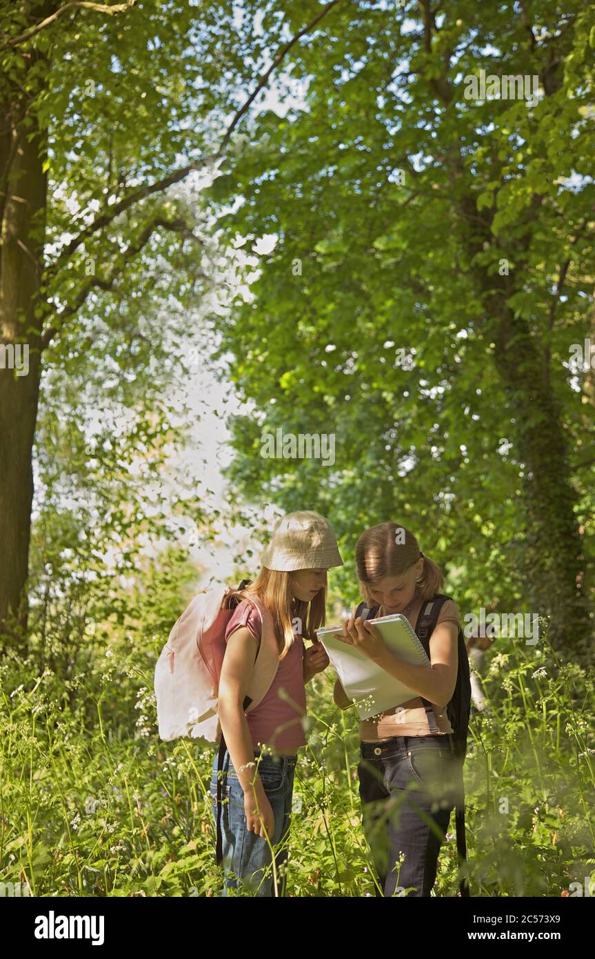 Girls with notebook on field trip in woods Stock Photo