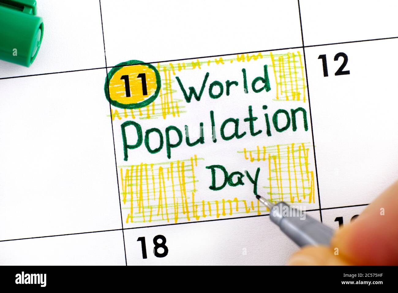 Woman fingers with pen writing reminder World Population Day in calendar. July 11 Stock Photo