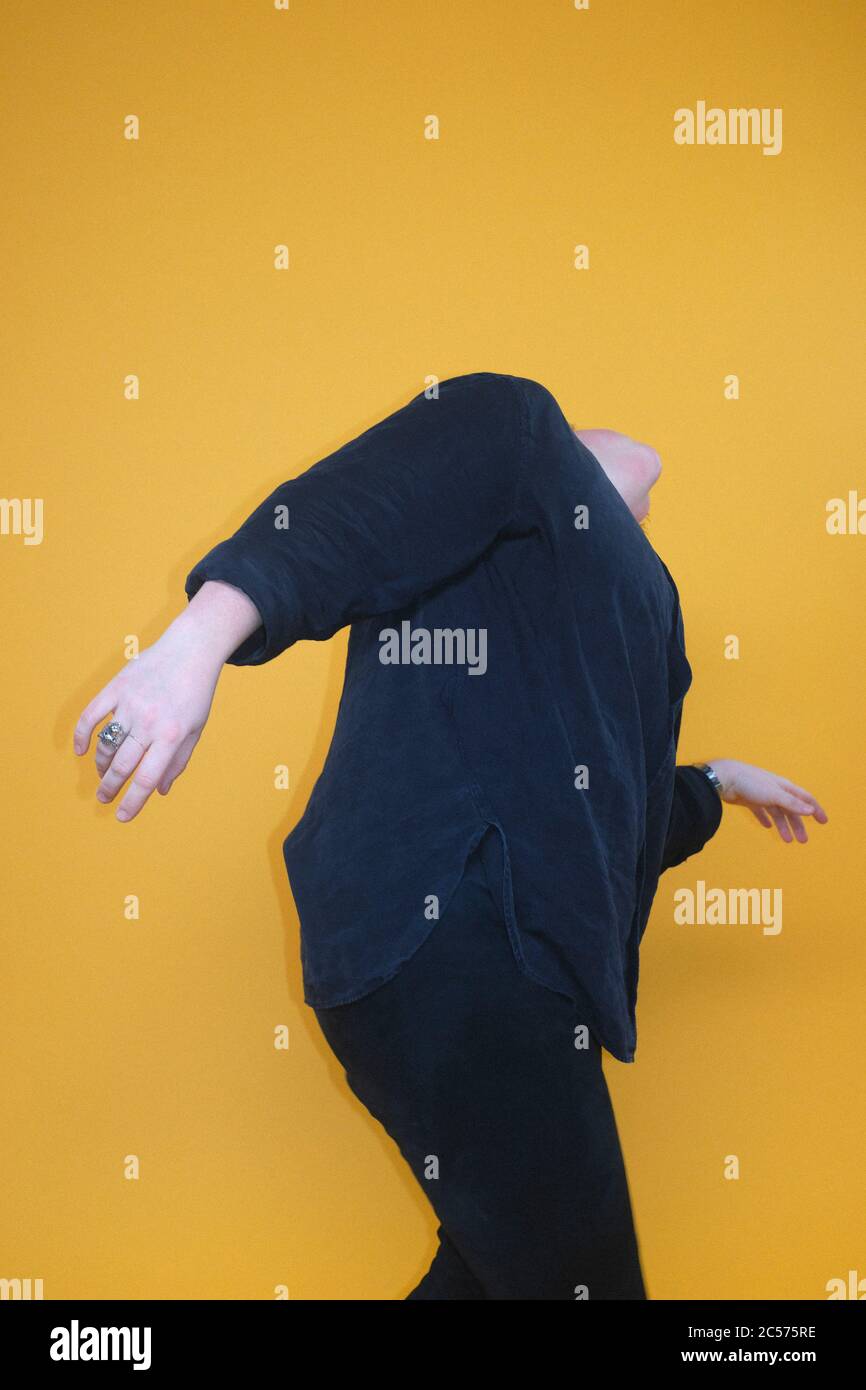 Carefree woman dancing against yellow background Stock Photo - Alamy