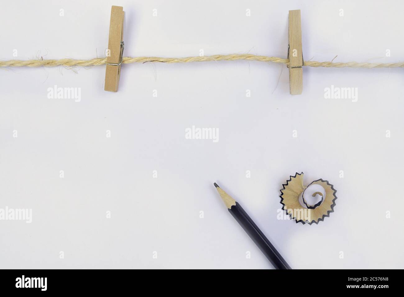 Wooden clothespins hanging on a rope with a pencil and pencil shavings ...