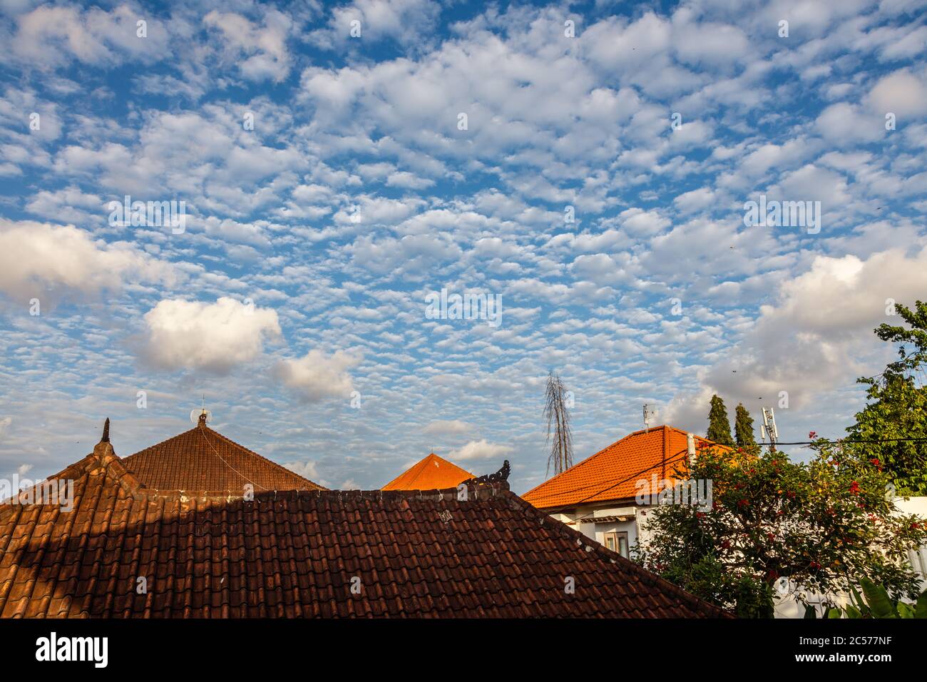 Blue sky with many little white clouds over the roofs of a village. Badung, Bali, Indonesia, Stock Photo