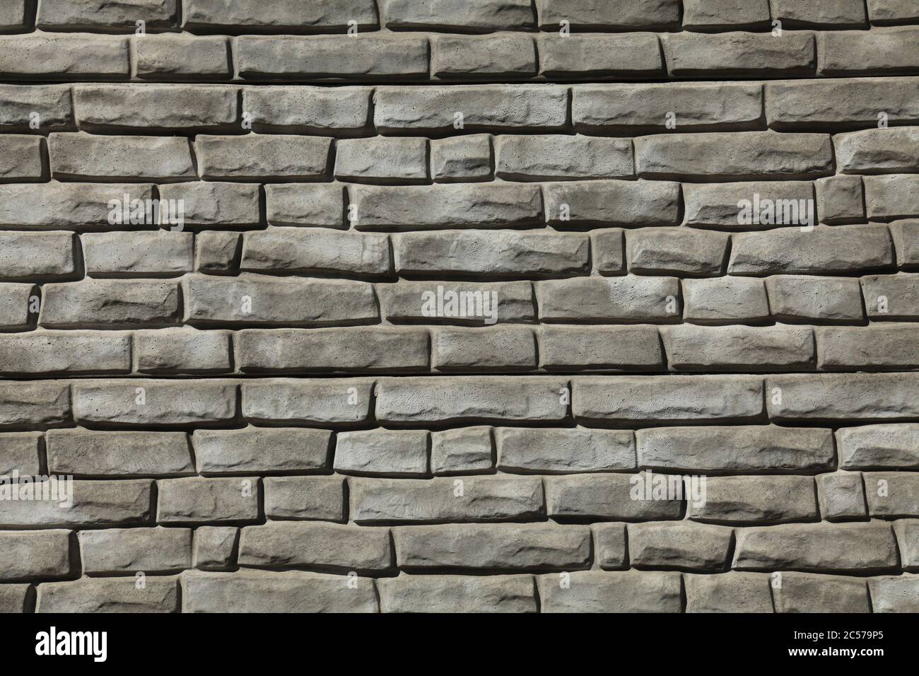 Brick wall texture, background in grey, faded color. Masonry-style concrete wall. Stylish fencing, made of decorative stone. Modern fashionable design Stock Photo