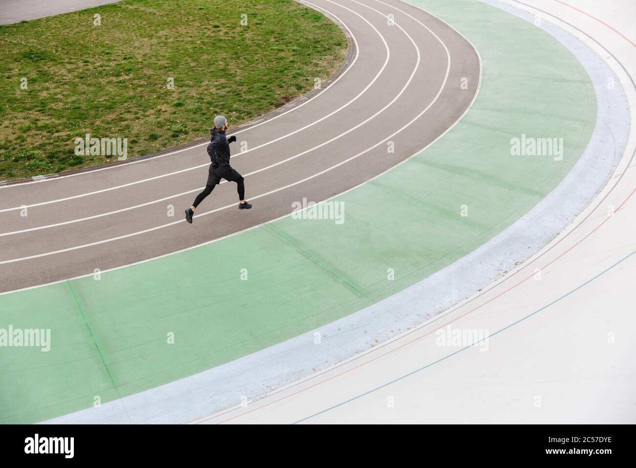 Confident young fit sportsman running on the race track at the stadium outdoors Stock Photo