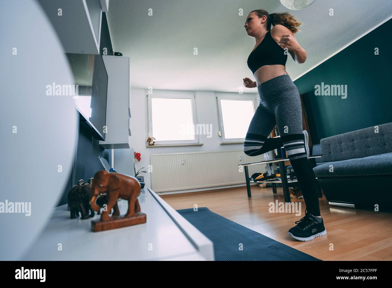 Europe, Germany, Rosenheim, Young Female is doing Sports Workout at Home, Livingroom Stock Photo