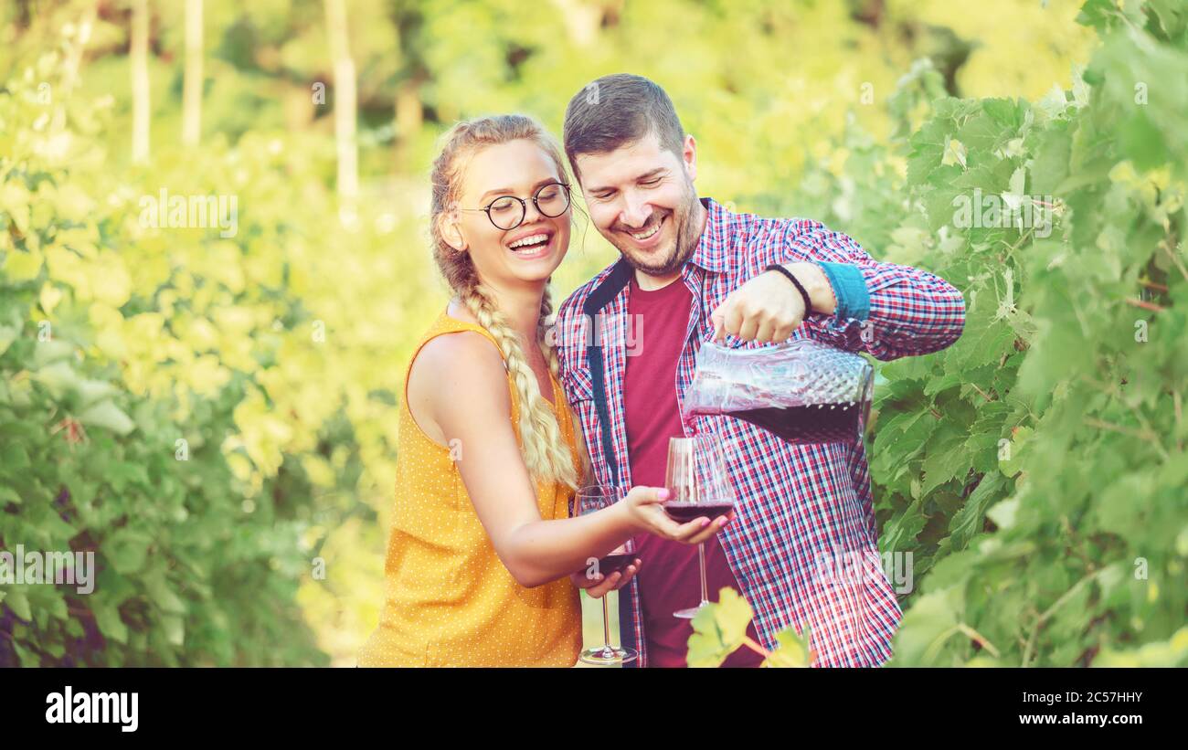 Happy couple tasting red wine sample in vineyard farm enjoying harvesting weekend day tour Stock Photo