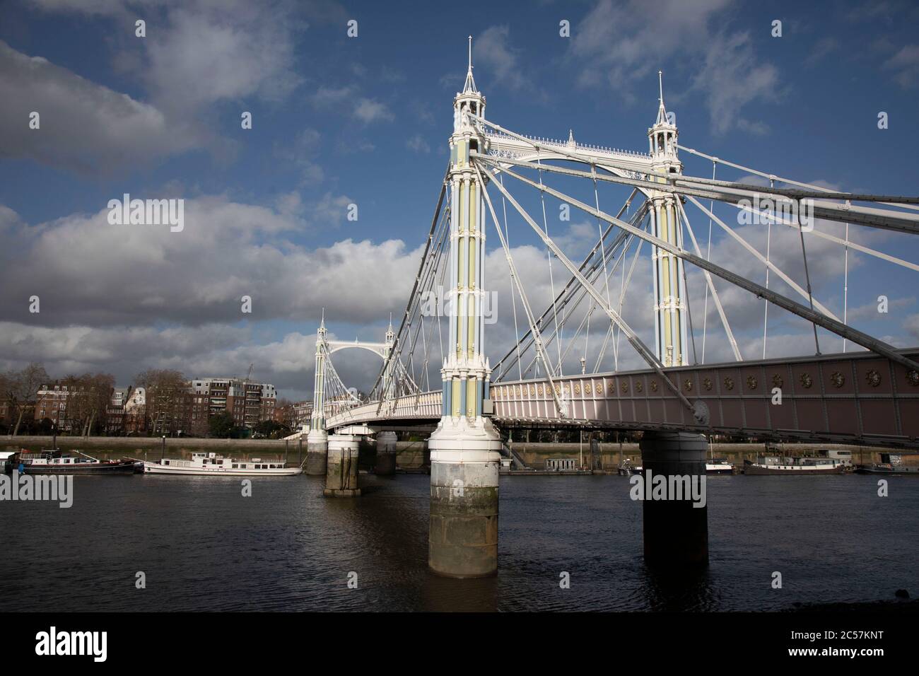 View across the River Thames path on the South side at Battersea looking towards Chelsea over Albert Bridge on 1st February 2020 in London, England, United Kingdom. Albert Bridge is a road bridge over the Tideway of the River Thames connecting Chelsea in Central London on the north, left bank to Battersea on the south. Designed and built by Rowland Mason Ordish in 1873. Stock Photo