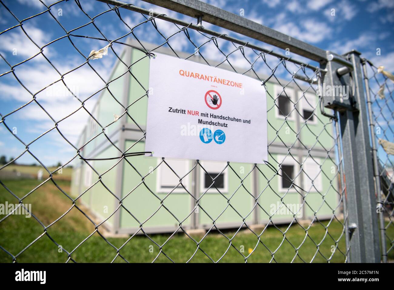 01 July 2020, Bavaria, Pöcking: A sign with the inscription 'Quarantine zone - access only with gloves and mouth protection' is visible on a fence in front of a residential container facility for refugees. Following a massive outbreak of the corona virus at a caterer in Gilching, the district administration has now closed four asylum-seeker accommodation facilities where employees of the company live. The more than 90 residents of the facility are to be tested for the corona virus on that day. Photo: Matthias Balk/dpa Stock Photo