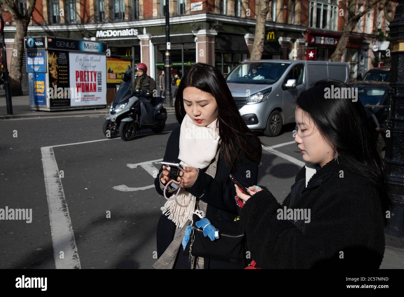 Two Chinese woman checking their smart phones on 18th February 2020 in London, England, United Kingdom. Stock Photo