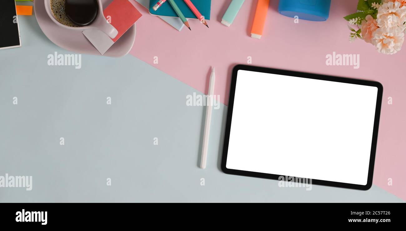 The top view image of two tones table is surrounding by a white screen tablet and equipment. Stock Photo