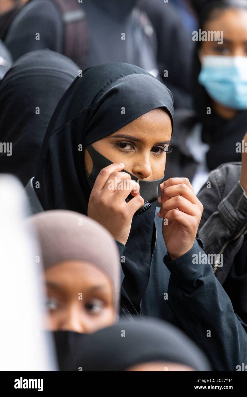 A young woman adjusts her face mask at a Black Lives Matter demonstration, Parliament Square, London, 27 June 2020 Stock Photo