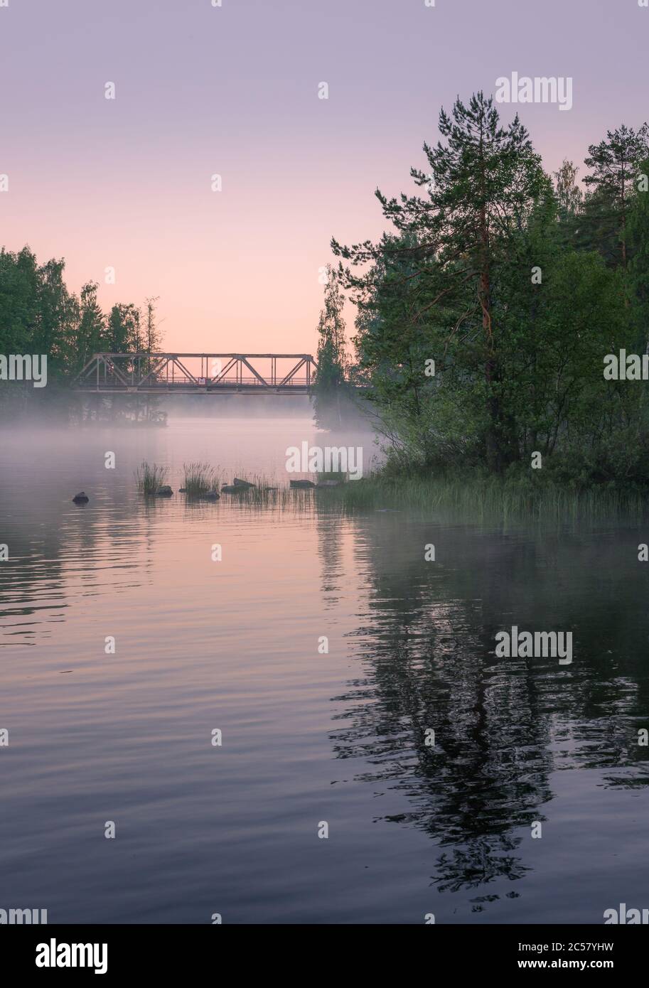 Foggy summer landscape and old iron bridge with beautiful calm lake at summer night in Finland Stock Photo