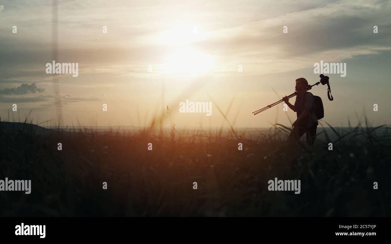 Man silhouette carrying tripod Stock Photo