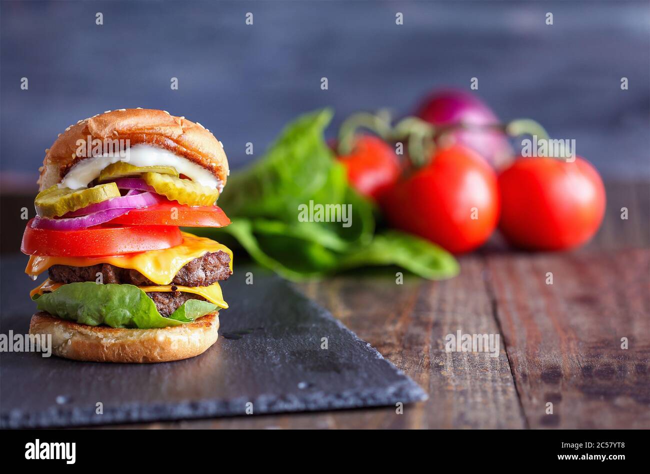 A big, fat, juicy double cheeseburger made with two 100% beef patties, slices of melted cheese, onions, pickles, lettuce, tomatoes, and mayo on a fres Stock Photo