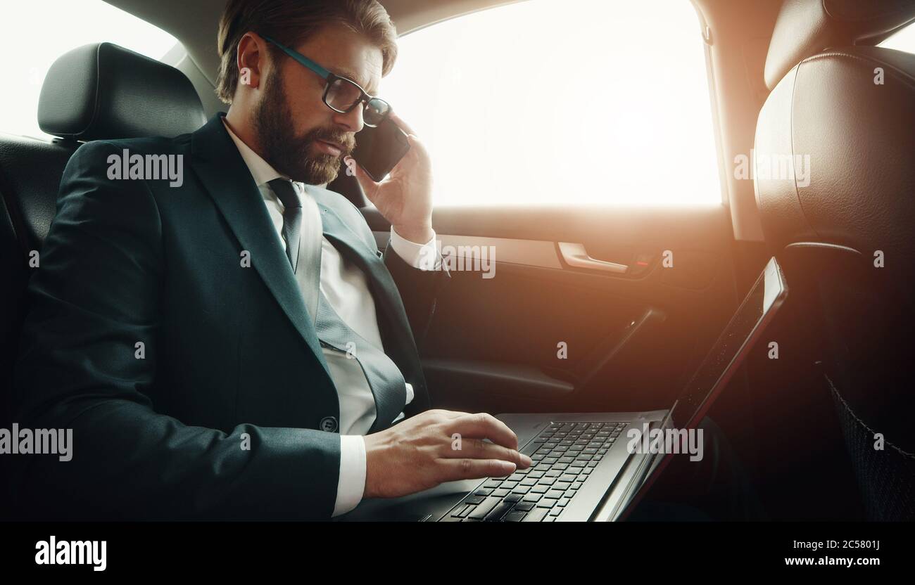 Businessman using gadgets in car Stock Photo