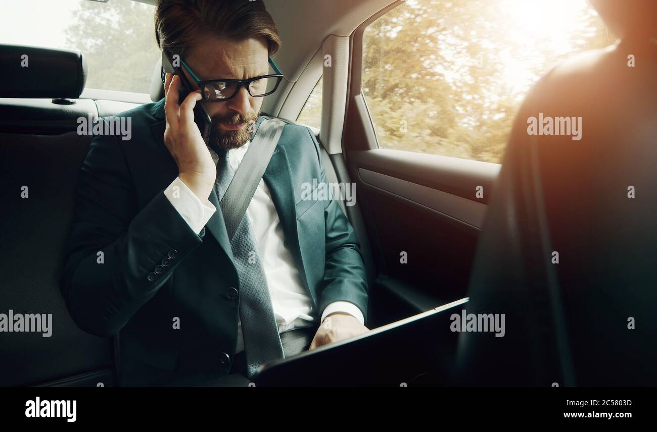 Businessman using electronics in car Stock Photo