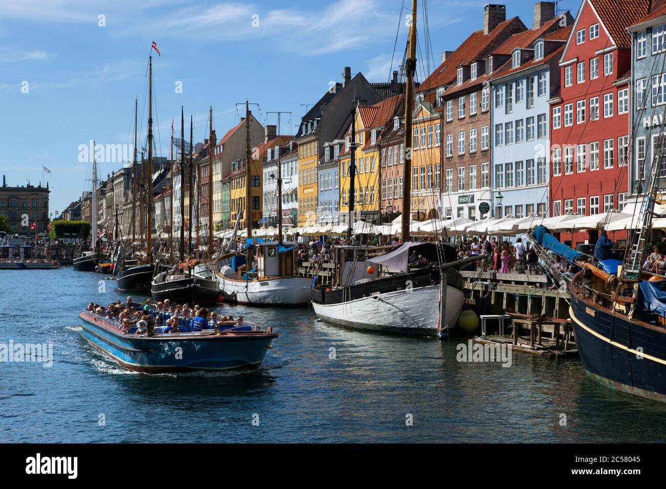Tour boat along Nyhavn (New Harbour) canal lined with boats and former merchant's houses Stock Photo