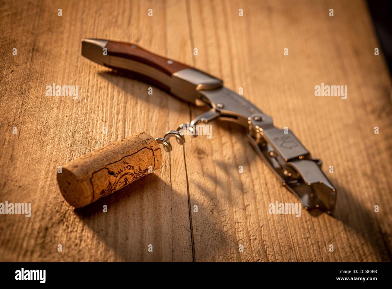 Corkscrew on sunlit wooden table with cork Stock Photo Alamy