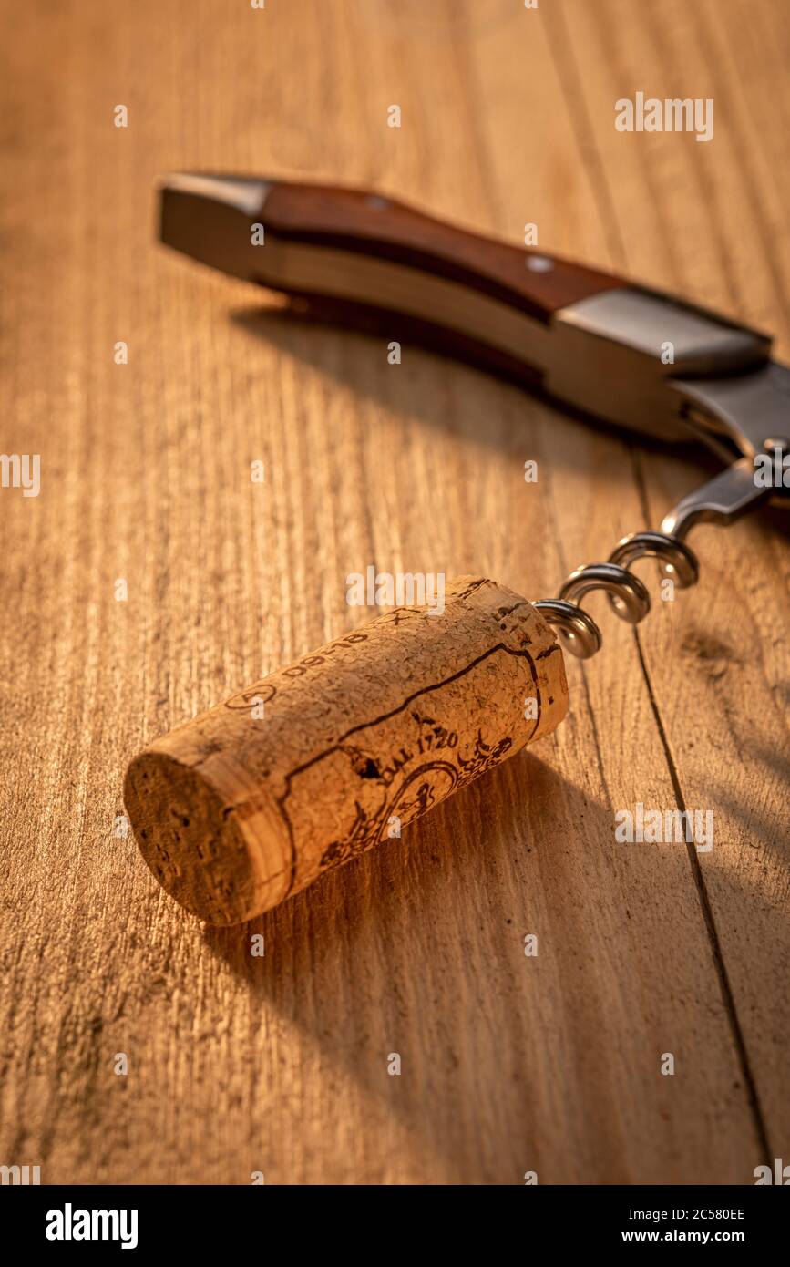 Corkscrew on sunlit wooden table with cork Stock Photo