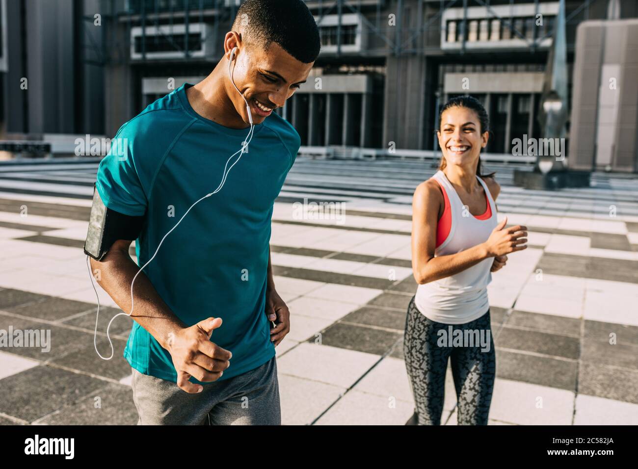 Smiling man and woman on a morning run. Two people in sportswear exercising together in the city. Stock Photo