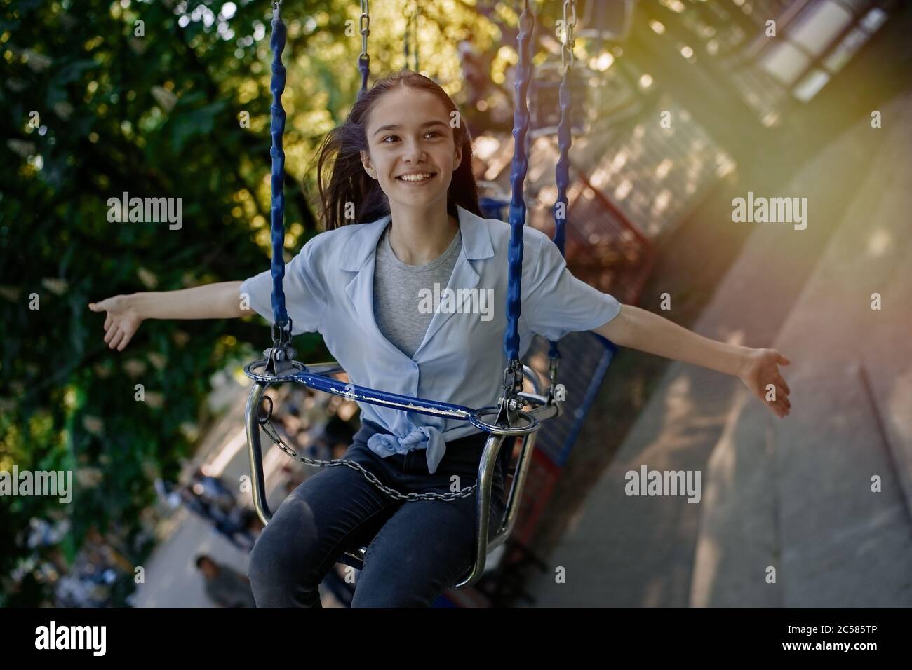 Happy child teenage girl riding chain carousel swing at amusement park Stock Photo