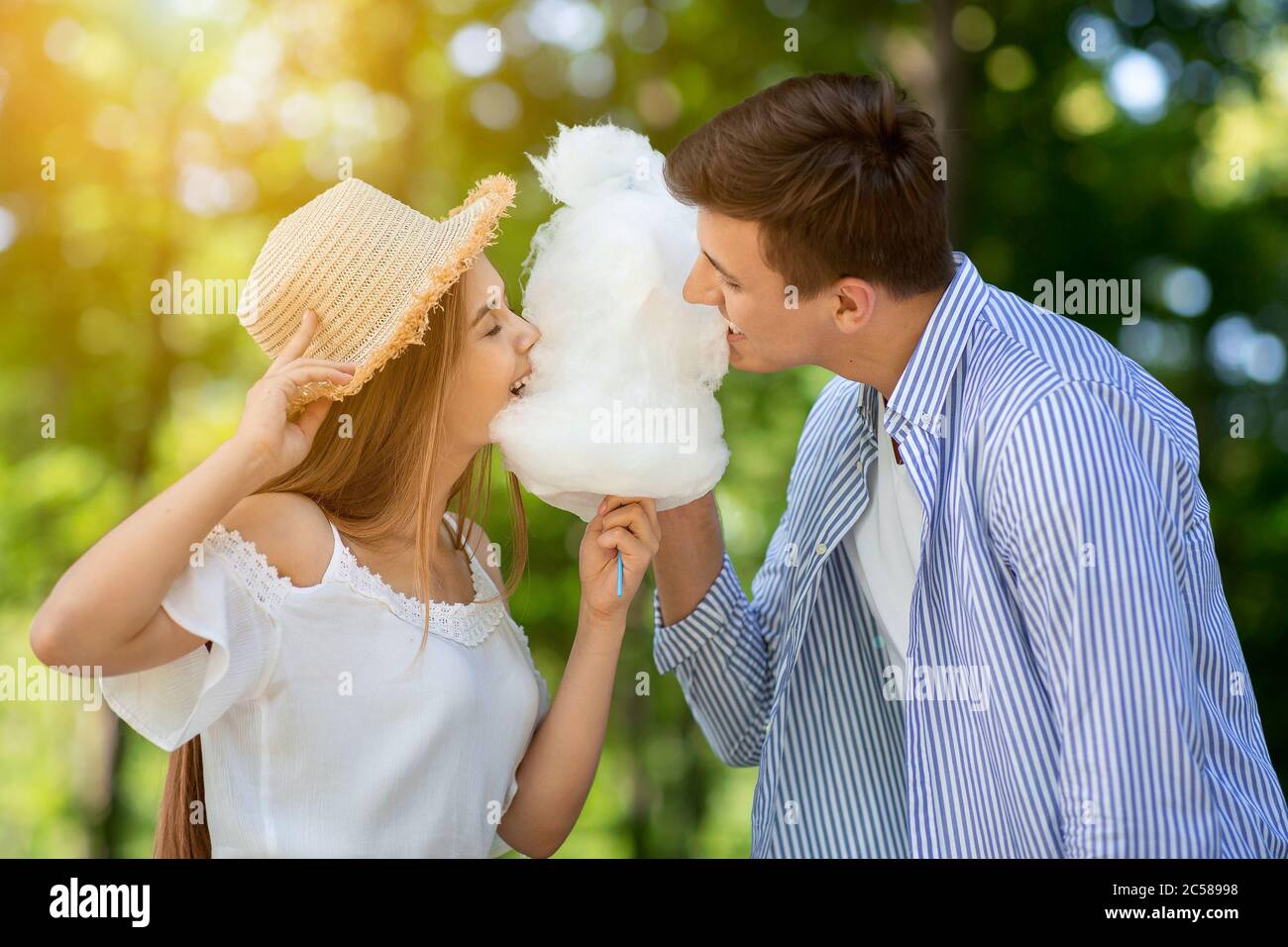 Lovely girl with her boyfriend eating cotton candy together at park