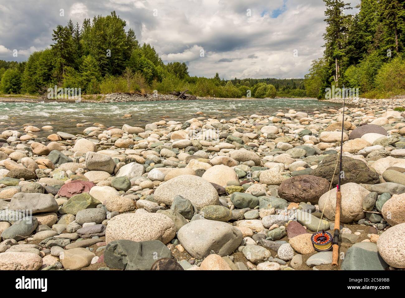 Fly rod resting on boulders beside the fast flowing Kitimat river in British Columbia, Canada. Stock Photo