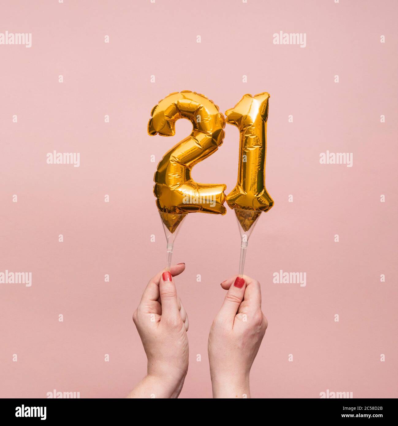 Female hand holding a number 21 birthday anniversary celebration gold balloon Stock Photo